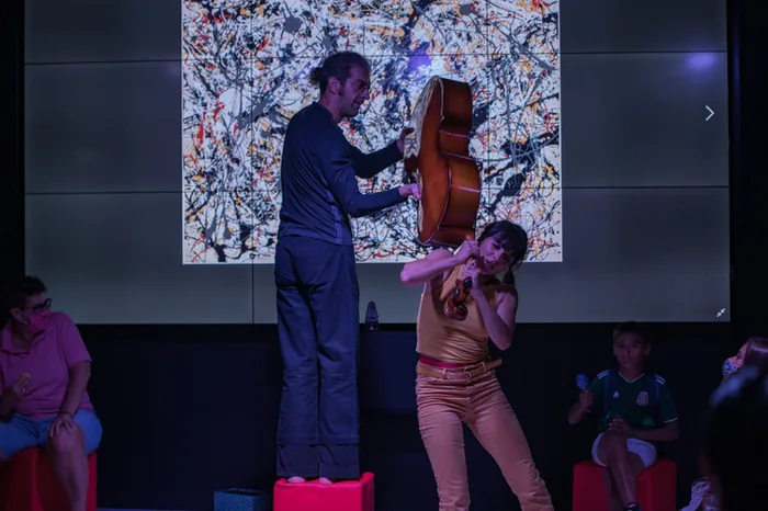 La violoncelliste jouant, la danseuse en suspension derrière elle