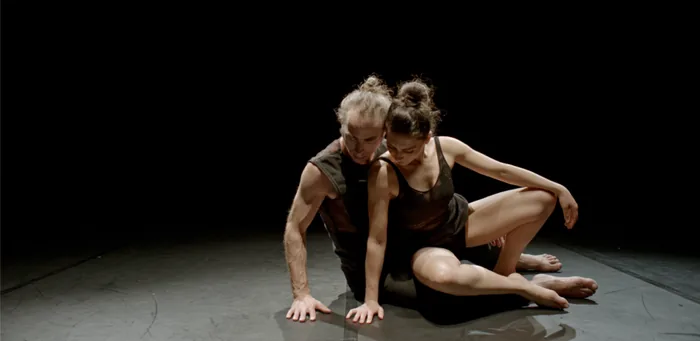 Une danseuse et un danseur enlacés au plateau, dans un clair-obscur