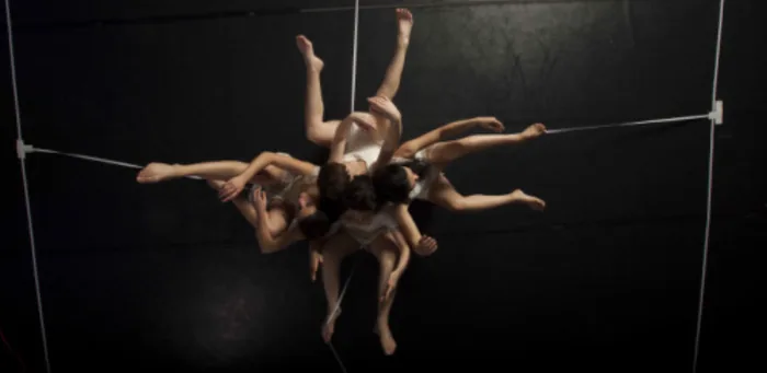 Une danseuse de dos face à un mur, dans une lumière contrastée