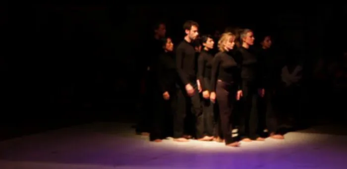 Une danseuse seule au plateau, bras tendu vers le haut, dans une lumière rasante